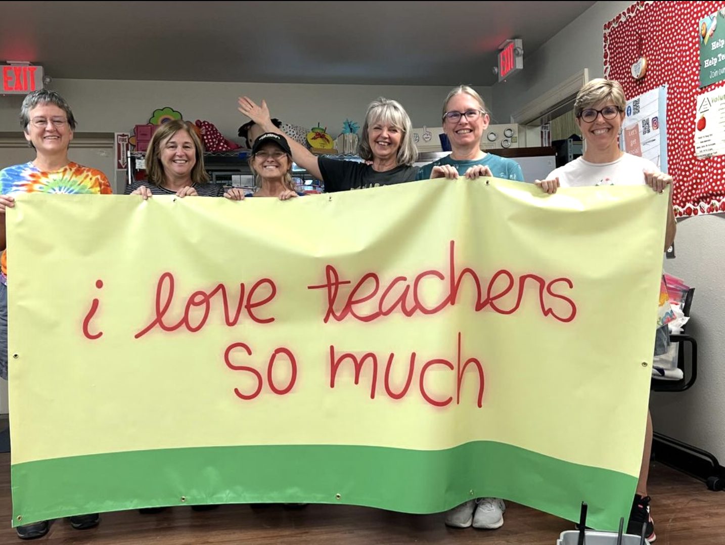 Seven Teacher Reuse volunteers in the store holding a banner reading “i love teachers so much”